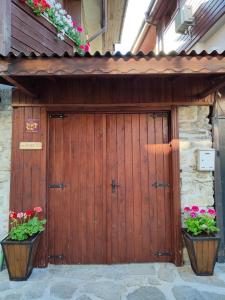 a wooden garage door with two pots of flowers at Guest Rooms Melsambria in Nesebar