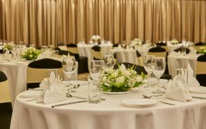 une salle à manger avec des tables et des chaises blanches et des fleurs blanches dans l'établissement Signature Club Resort, à Devanhalli