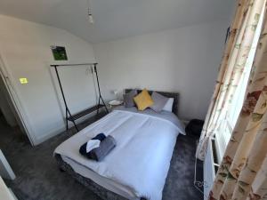 um quarto com uma cama com lençóis brancos e almofadas em Three bedroom House em Londres