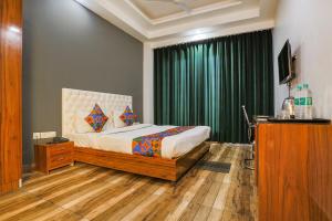 FabHotel Skylight Inn Near Medanta Hospital في جورجاون: غرفة نوم بسرير وستارة خضراء