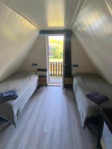 two beds in a room with a large window at De Waterlelie gezellig en sfeervol aan het water in Gramsbergen