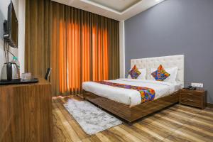 FabHotel Skylight Inn Near Medanta Hospital في جورجاون: غرفة نوم بسرير وستارة برتقال