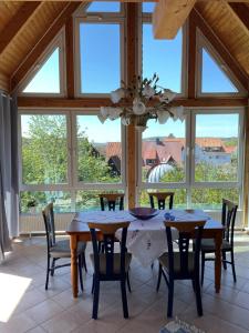 jadalnia ze stołem, krzesłami i oknami w obiekcie Ferienwohnung Oda w mieście Bad Gandersheim