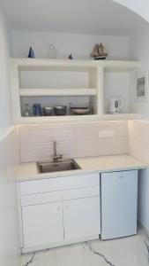 una cucina con armadi bianchi e lavandino di Augusta Studios & Apartments a Naoussa