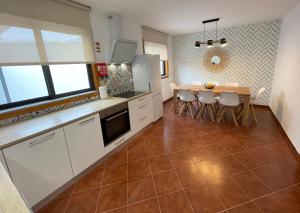 a kitchen with white cabinets and a table and chairs at House 9 Guimarães in Guimarães