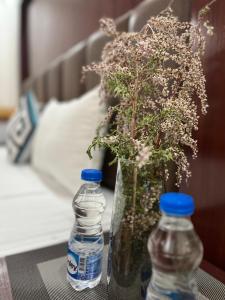 zwei Flaschen Wasser und eine Vase mit Blumen auf dem Tisch in der Unterkunft Ladakh Country Inn in Leh