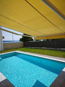 ein Schwimmbad mit gelbem Regenschirm darüber in der Unterkunft Holiday house NiRi with a heated outdoor pool /BBQ in Kaštela