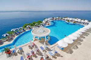 an overhead view of a resort pool with chairs and umbrellas at Korumar Hotel Deluxe in Kuşadası