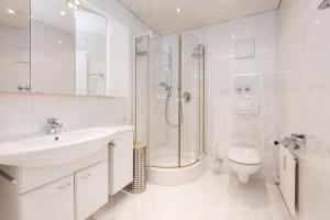 a white bathroom with a shower and a sink and a toilet at Spacious Corner apartment in Aparthotel Kleinwalsertal in Mittelberg