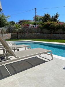 uma piscina com duas cadeiras e uma mesa e uma piscina em Cost Mari Almyrida New by ZAGO Boutiqe hotels em Almirída