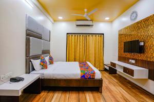 a bedroom with a bed and a flat screen tv at FabHotel Tanishq in Sinnar