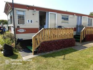 a house with a wooden fence in front of it at Gina's Static caravan,118 Sandsgate in Hemsby