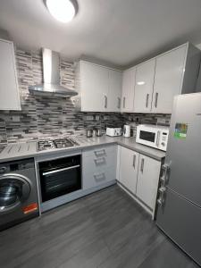 a kitchen with white cabinets and a refrigerator at Mona's Home in Dagenham