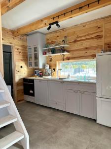 - une cuisine avec des placards blancs et des murs en bois dans l'établissement Domki na Mazurach - Marksewo, à Szczytno