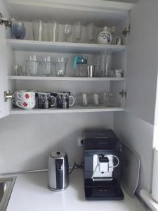 a kitchen with a coffee maker and cups on shelves at domek Lawendowy na wiejskiej in Lubiatowo