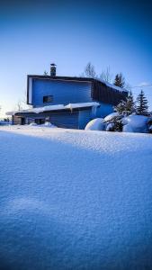 a snow covered yard with a building in the background at Yukiumi House in Kamikawa