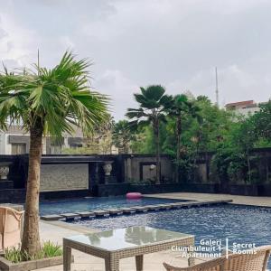 - une piscine avec une table et un palmier dans l'établissement Ciumbuleuit Apartment by Secret Rooms, à Bandung