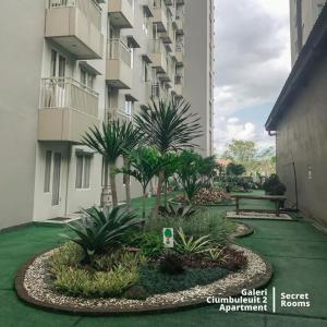 a garden in front of a building with palm trees at Ciumbuleuit Apartment by Secret Rooms in Bandung
