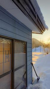 a house with snow on the side of it at Yukiumi House in Kamikawa