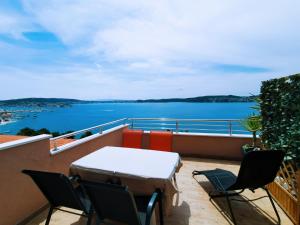 een balkon met een tafel en stoelen en uitzicht op het water bij Apartment Jurčević in Trogir
