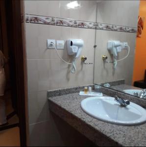 bagno con lavandino e telefono appeso al muro di Hotel Les Ambassadeurs a Orano