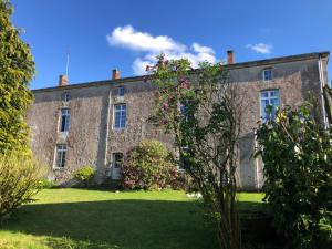 une vieille maison en pierre avec des fleurs dans la cour dans l'établissement Gîte du Sacré-Coeur - 25 mn du Puy du fou, à Saint-Aubin-de-Baubigné