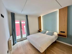 um quarto com uma cama branca e uma grande janela em Apartamento junto a la catedral VuT 09-0443 em Burgos
