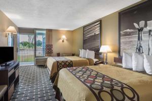 a hotel room with two beds and a flat screen tv at Super 8 by Wyndham Ocala I-75 in Ocala