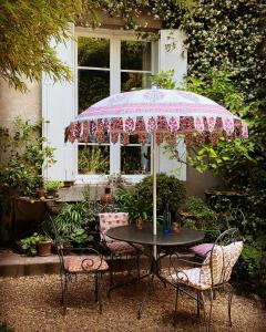 a table with a pink umbrella in front of a house at Le logis blanc bed&breakfast in Coursan