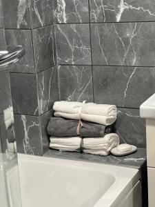a pile of towels sitting next to a bath tub at Mona's Home in Dagenham
