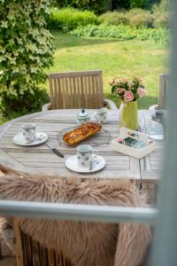 una mesa de madera con tazas y platos de comida. en Wuytershoef, en Dilsen-Stokkem