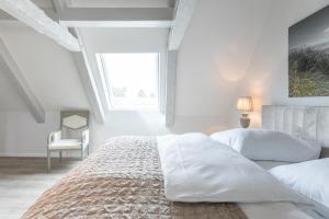 a white bedroom with two beds and a window at Nordisch noble Lebensart WE 1 in Bargum