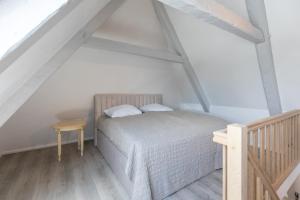 a white bedroom with a bed and a wooden floor at Nordisch noble Lebensart WE 2 in Bargum