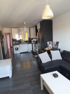uma sala de estar com um sofá preto e uma cozinha em Bright top floor apartment! em Zakynthos