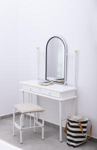a white dressing table with a mirror and a stool at Lychnos apartments in Kamilari