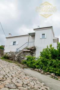uma casa branca com uma estrada de pedra em frente em Casa da Calçada Guest House em Pinhão