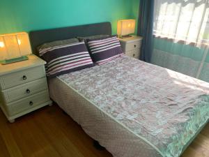 a bedroom with a bed with two night stands and two lamps at Corio (Geelong) Holiday Villa in Corio