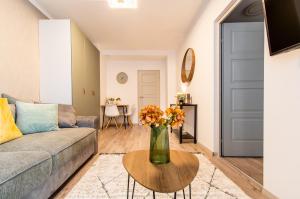 uma sala de estar com um sofá e um vaso de flores sobre uma mesa em Alex Apartman em Szombathely