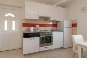 - une cuisine avec des appareils électroménagers blancs et une porte blanche dans l'établissement Apartmani Grga, à Trogir