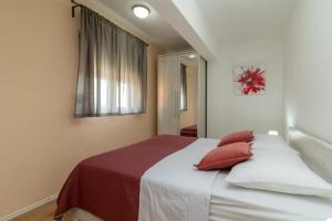 - une chambre avec un lit doté d'oreillers rouges dans l'établissement Apartmani Grga, à Trogir