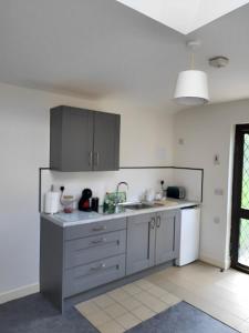 a kitchen with gray cabinets and a sink at Oak Cottage 3 km from Rock of Cashel in Cashel