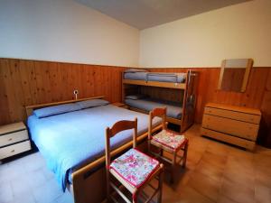 a bedroom with a bed and two chairs in it at APPARTAMENTO S.ANNA IN VALMALENCO in Torre di Santa Maria