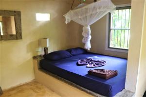 a bedroom with a bed with blue sheets and a window at The Spice House Mirissa in Mirissa