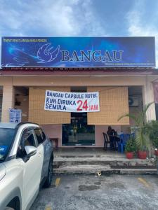 een auto geparkeerd voor een restaurant bij Bangau - Short Term Rest Area Capsule Hotel in Sepang