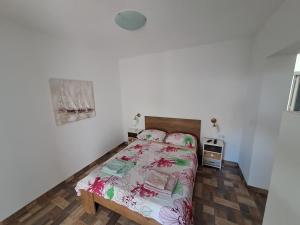 Schlafzimmer mit einem Bett mit rosa und grüner Bettwäsche in der Unterkunft BenJak Apartments in Hvar