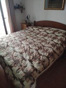 ein Bett mit einer Decke in einem Schlafzimmer in der Unterkunft Casa Isabella II, trilocale in Erbezzo in Erbezzo