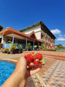a person holding a bowl of strawberries in front of a building at Khushi Riverside Resort & Spa in Mahabaleshwar