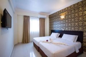 a hotel room with two beds and a television at Hotel Sea Princess in Teluk Bahang