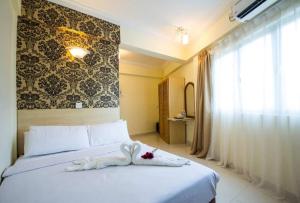 a bedroom with a white bed with a towel on it at Hotel Sea Princess in Teluk Bahang