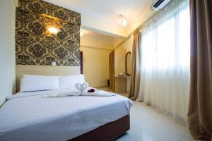 a bedroom with a bed with a white blanket and a window at Hotel Sea Princess in Teluk Bahang